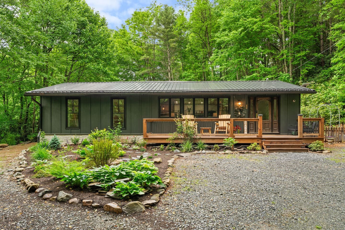 Wildwood Retreat cabin with lit windows, front deck and garden in the woods
